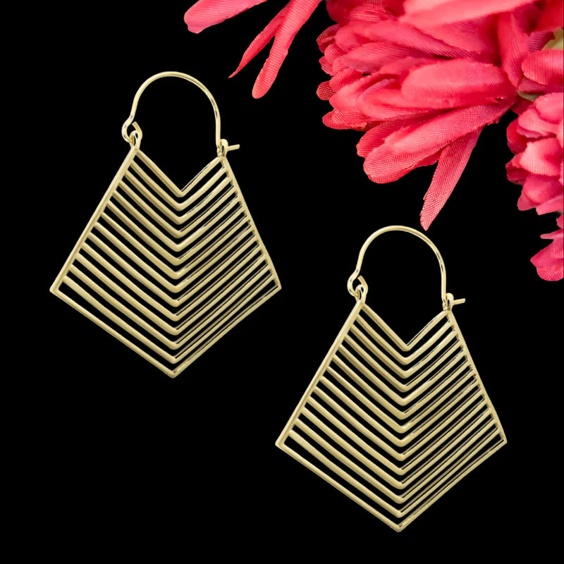 Layered brass gold hoop earrings displayed on black background, showcasing refined lines and contemporary design.