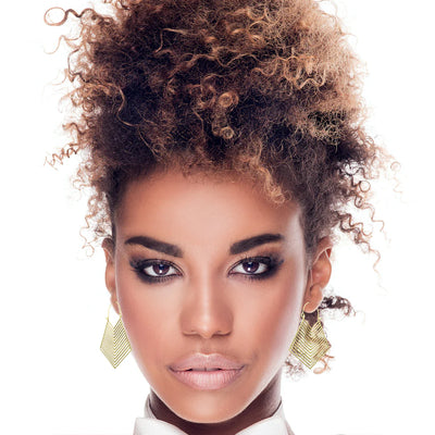 Woman wearing geometric brass gold hoop earrings, showcasing bold and artistic statement style with modern elegance.