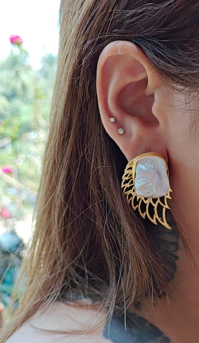 Woman wearing gold pearl wing earrings, showcasing intricate handcrafted design with organic baroque pearls.