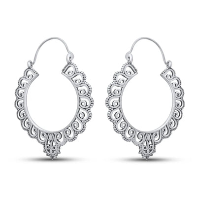 Angled view highlighting design texture of chunky silver floral hoop earrings.
