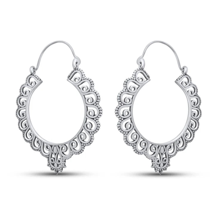 Angled view highlighting design texture of chunky silver floral hoop earrings.