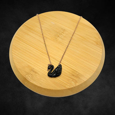 Black swan pendant necklace displayed on wooden round base, elegant crystal jewelry.