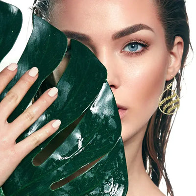Editorial photo of model wearing gold plated oval branch dangle earrings, elegant designer jewelry.