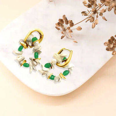 Flat lay of emerald pearl cluster hoop earrings on marble background, delicate statement jewelry.