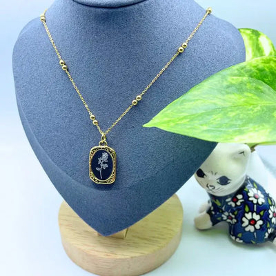 Dark blue enamel floral pendant necklace with gold border, refined everyday accessory.