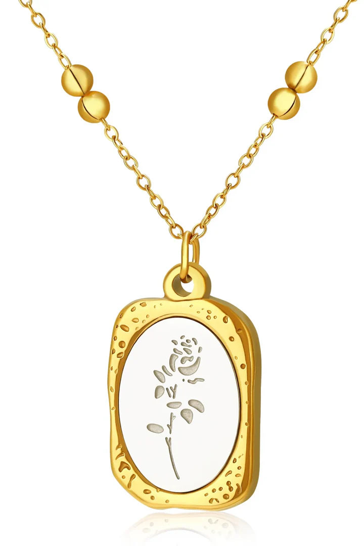 Front view of gold enamel floral pendant necklace with white enamel floral pattern.