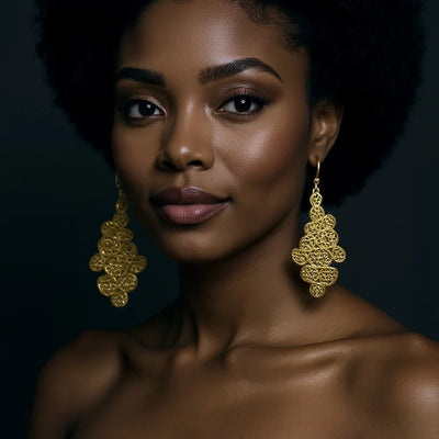 Model wearing gold filigree leaf drop earrings, elegant statement accessory.
