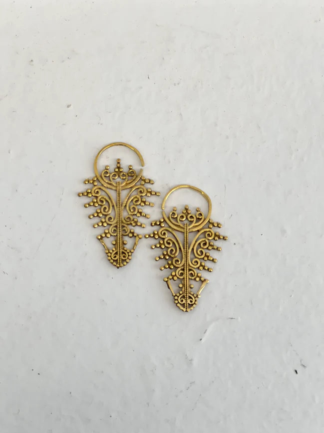 Golden filigree leaf earrings displayed on textured white background, handcrafted ethnic jewelry.