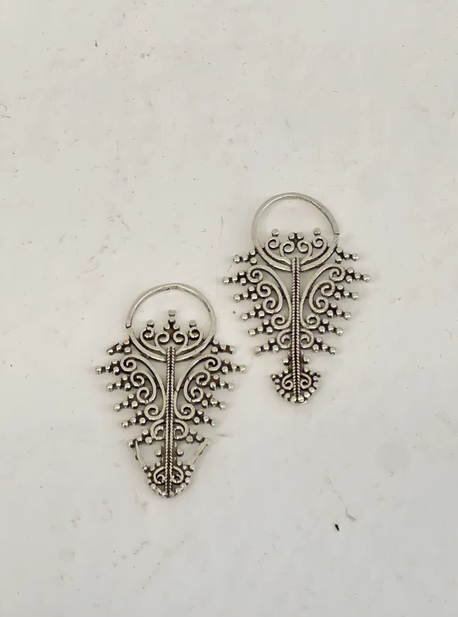 Golden filigree earrings laid flat on textured surface, intricate handcrafted jewelry design.
