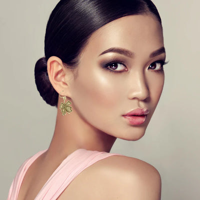 Model wearing golden four-leaf clover earrings, elegant and feminine fashion accessory.