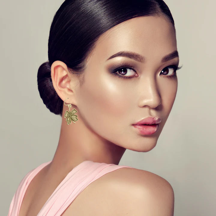 Model wearing golden four-leaf clover earrings, elegant and feminine fashion accessory.
