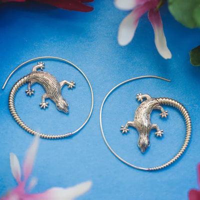 Pair of golden lizard hoop earrings on colorful background, stylish nature-themed design.