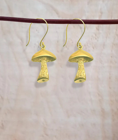 Pair of golden mushroom earrings hanging on wooden rod, handcrafted style.