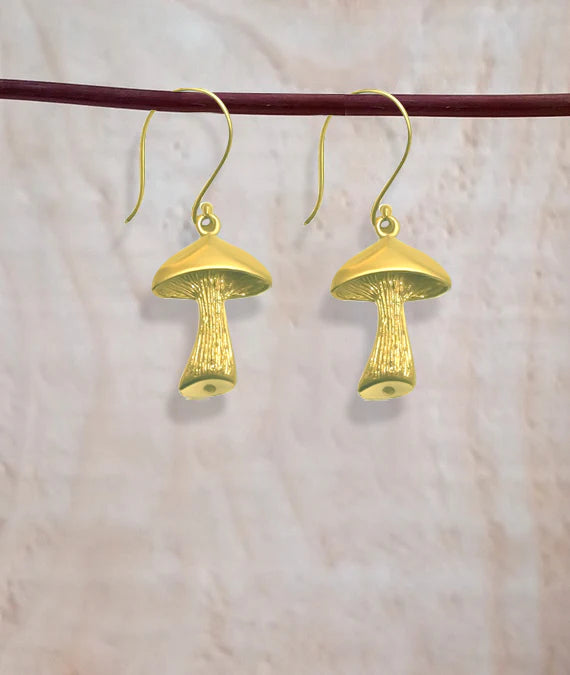 Pair of golden mushroom earrings hanging on wooden rod, handcrafted style.