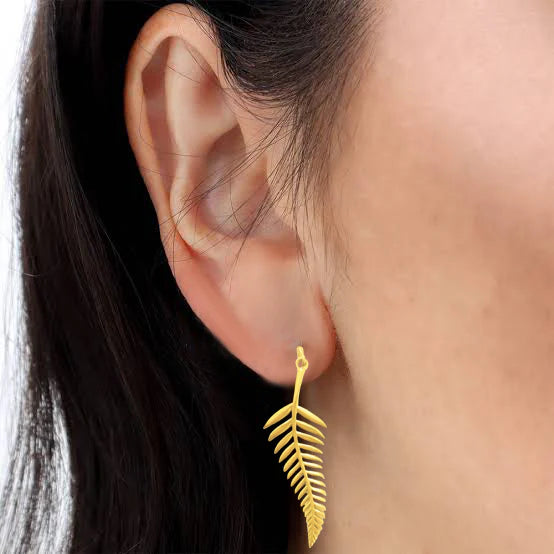 Model wearing golden palm leaf drop earrings, lightweight elegant accessory.