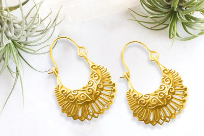 Flat lay of golden boho hoop earrings with ornate cutout pattern, ethnic-inspired jewelry.