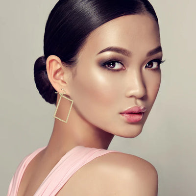 Model wearing golden rectangle frame drop earrings, sleek modern fashion accessory.