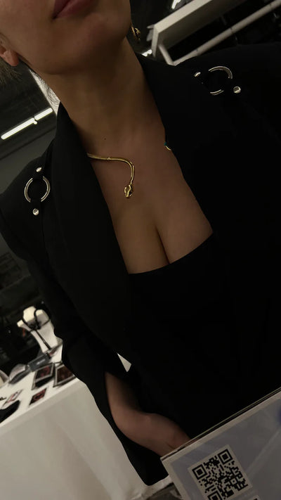 Close-up of model wearing golden snake collar necklace, elegant statement jewelry.