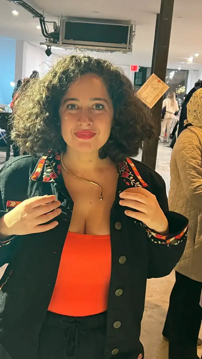 Model styling golden snake collar necklace at event, bold fashion look.