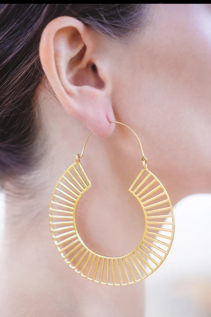 Model wearing extra large gold tracks hoop earrings showing elegant statement style.