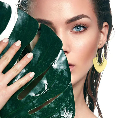 Model wearing gold plated basket twisted line long drop hoop earrings styled with modern minimal look.