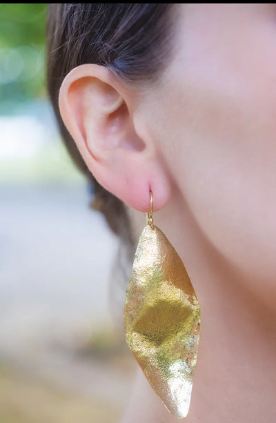 Close-up of model wearing long gold plated Fulani leaf drop earrings in side profile.