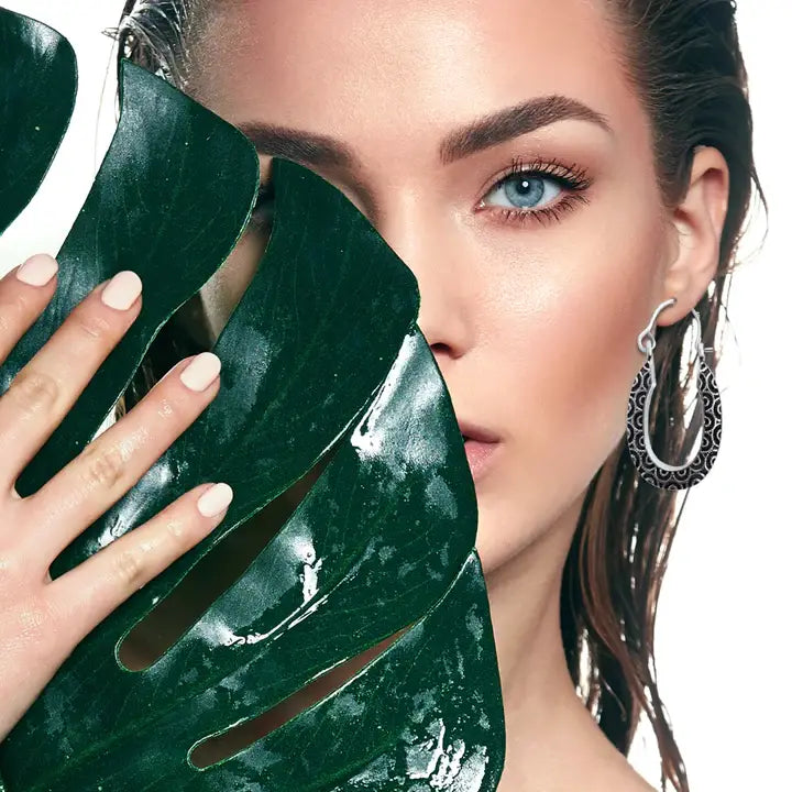 Model wearing sterling silver swirl black wavy design oval hoop earrings styled with bold elegant look.