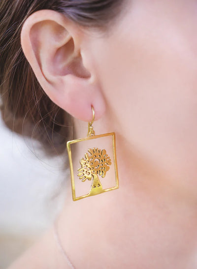 Model wearing elegant tree of life square gold earrings with fish hook design.