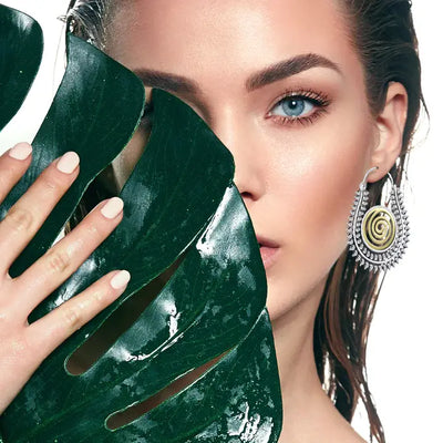 Model styling Warli design silver gold tone spiral handcrafted hoop earrings for an ethnic elegant look.