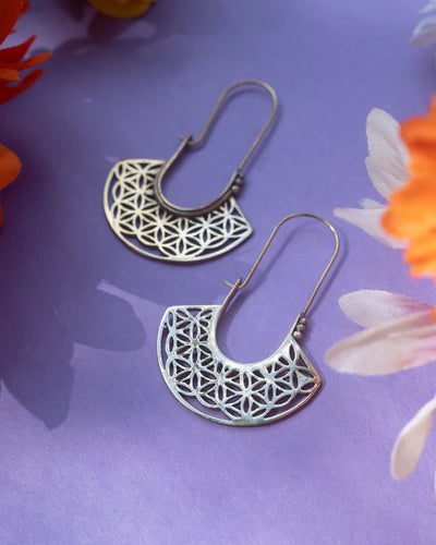 Pair of Flower Of Life Gold Metal Drop Earrings placed on a purple floral background.