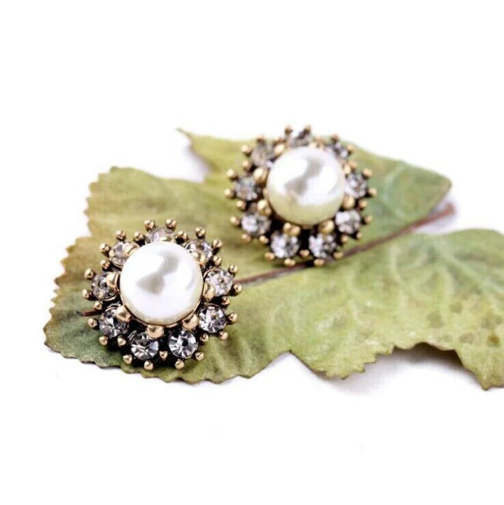 Pearl and Diamond Cluster Stud Earrings displayed on green leaf background.