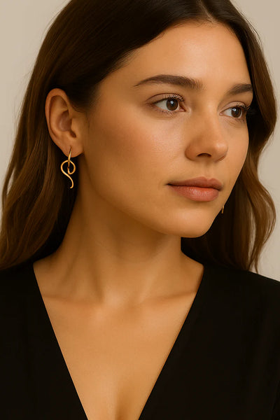 Model wearing serpentine glow skinny snake drop earrings, elegant modern style.