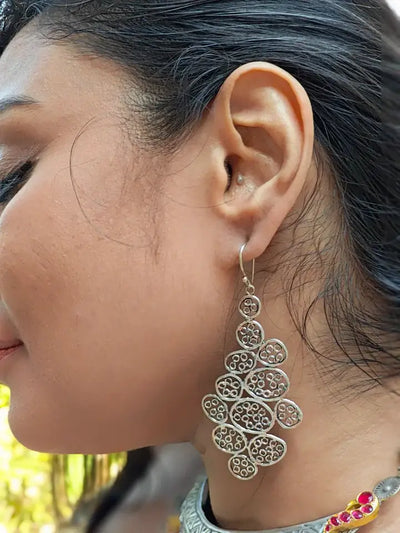 Model wearing silver filigree leaf drop earrings, detailed ethnic handcrafted jewelry.