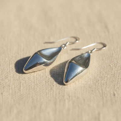pair of silver teardrop earrings on a beige fabric background