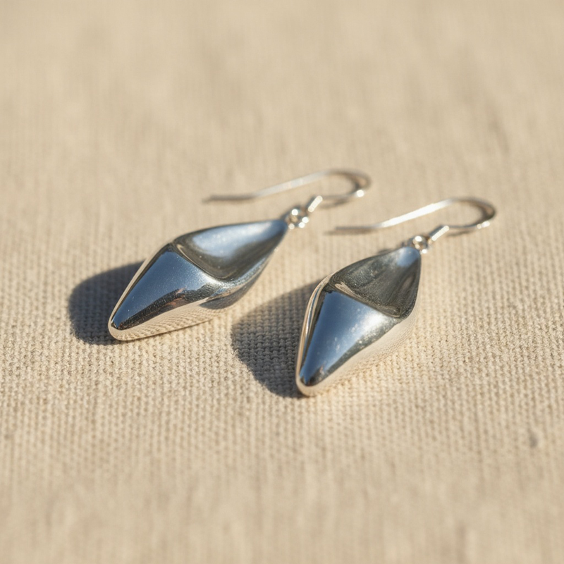 pair of silver teardrop earrings on a beige fabric background