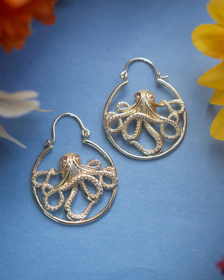 Silver Kraken octopus earrings displayed on blue background showing fine marine-inspired artistry.