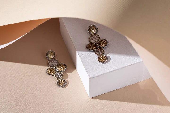 Two Tone Leaf Earrings on white arch stand showing lightweight design.